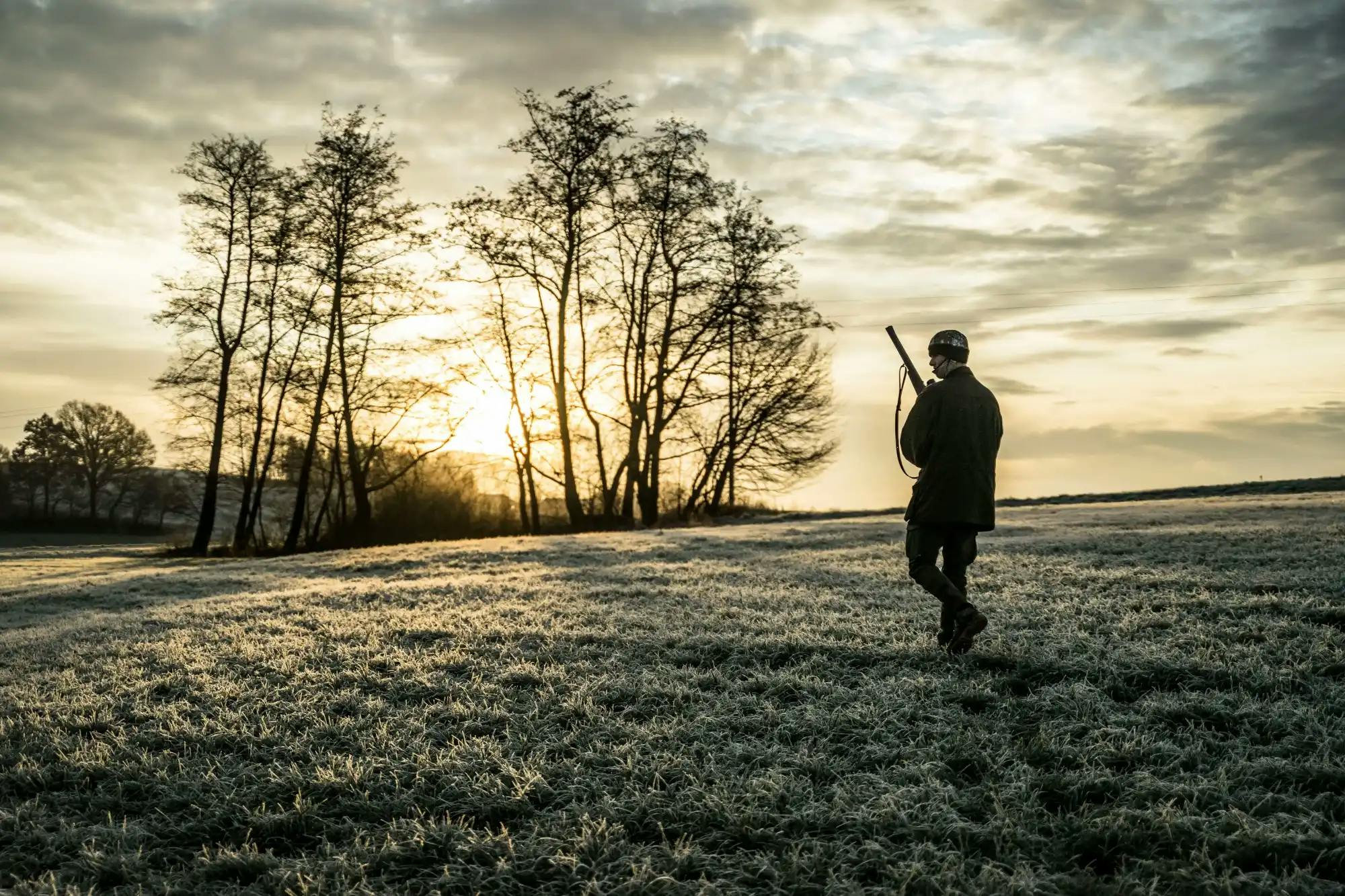 Cazador caminando por un campo congelado en el amanecer